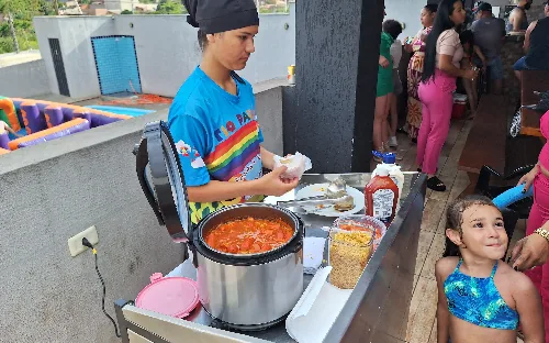 Monitora servindo hot dog com molho para as crianças