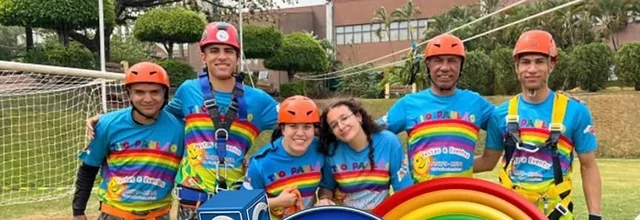 Equipe do Tio Paulão de capacete e cadeirinha, com as camisetas coloridas, no gramado do clube