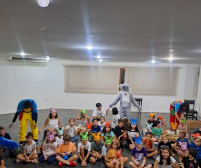 Grupo de crianças sentadas com o Coelho da Páscoa num salão