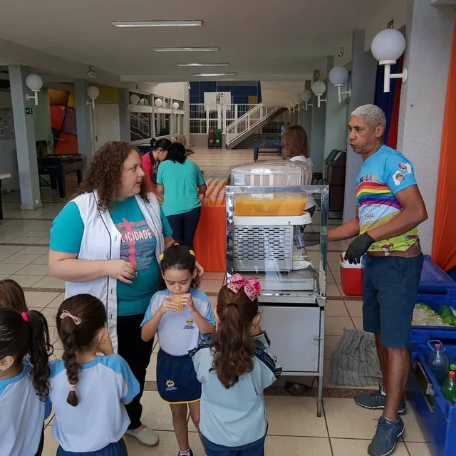 Tio Paulão servindo suco natural para crianças no colégio